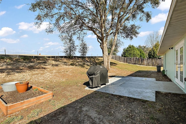 view of yard with a patio area, a fenced backyard, a vegetable garden, and french doors