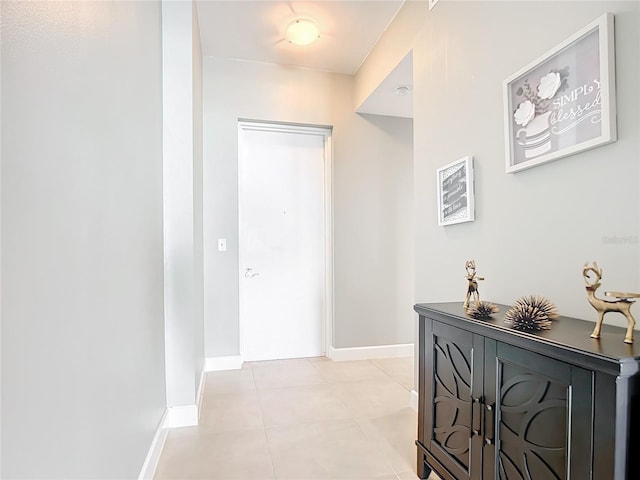 hallway with light tile patterned floors and baseboards