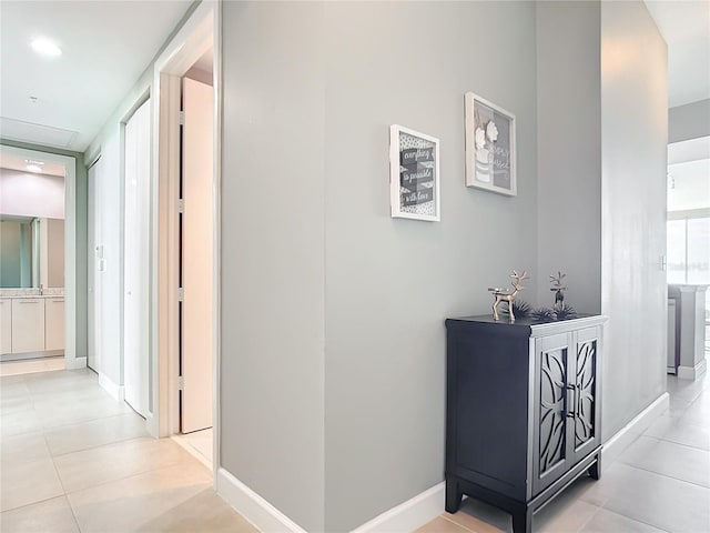 corridor featuring light tile patterned flooring and baseboards