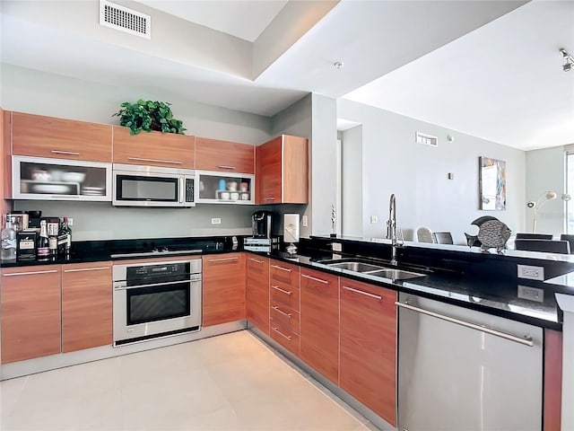 kitchen featuring appliances with stainless steel finishes, a sink, a peninsula, and modern cabinets