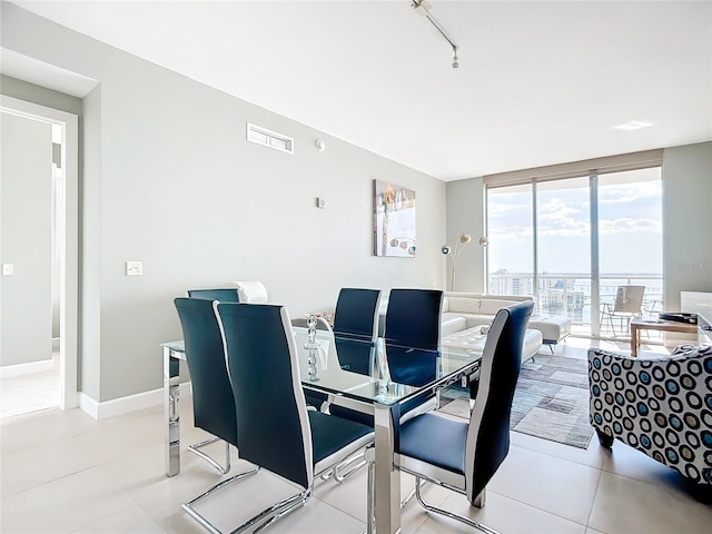 dining area featuring light tile patterned flooring, visible vents, baseboards, expansive windows, and rail lighting