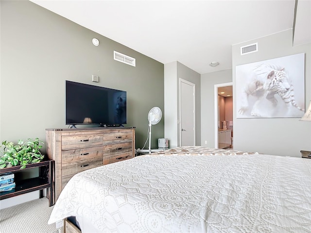 bedroom with carpet floors, visible vents, and ensuite bathroom