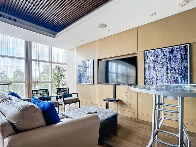 living area with a tray ceiling, floor to ceiling windows, and wood finished floors