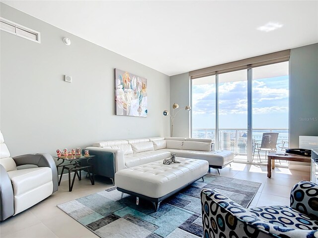 living room featuring light tile patterned floors, visible vents, and a wall of windows