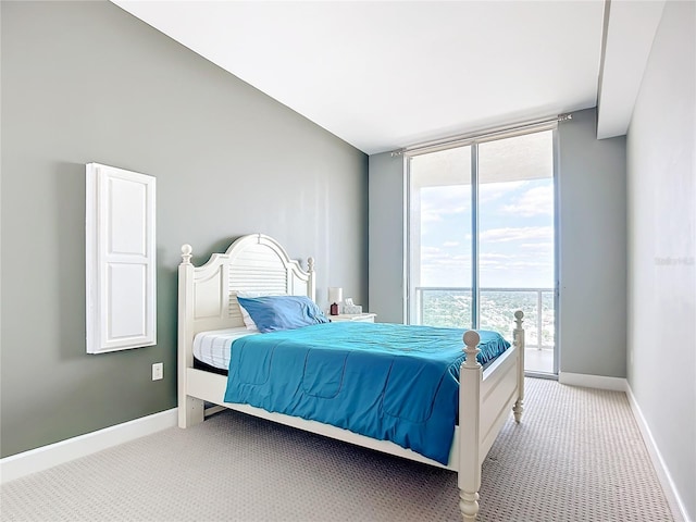 bedroom featuring light carpet, access to outside, baseboards, and a wall of windows