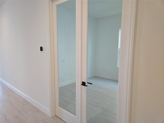 hall featuring light wood finished floors and baseboards