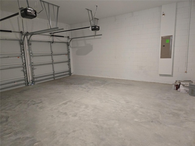 garage featuring concrete block wall, electric panel, and a garage door opener