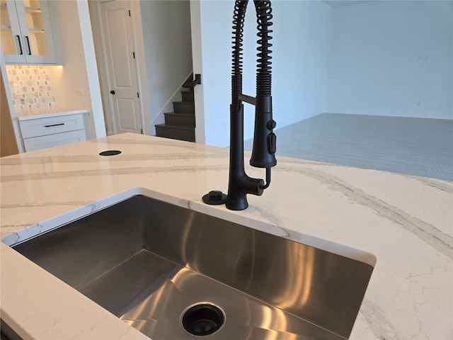 details with light stone counters, glass insert cabinets, a sink, and tasteful backsplash