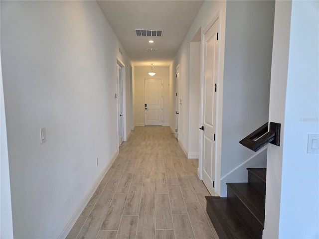 corridor with stairs, light wood finished floors, visible vents, and baseboards