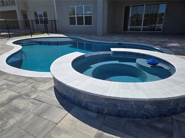 view of swimming pool featuring a patio area, fence, and a pool with connected hot tub