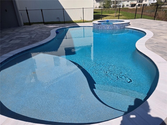 view of swimming pool featuring a pool with connected hot tub, fence, and a patio