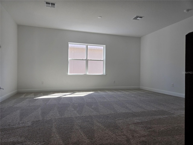 carpeted spare room with visible vents and baseboards