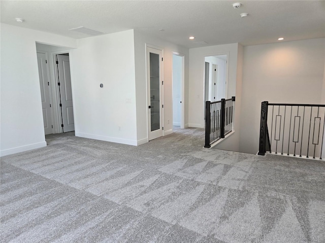 carpeted spare room with baseboards, visible vents, and recessed lighting