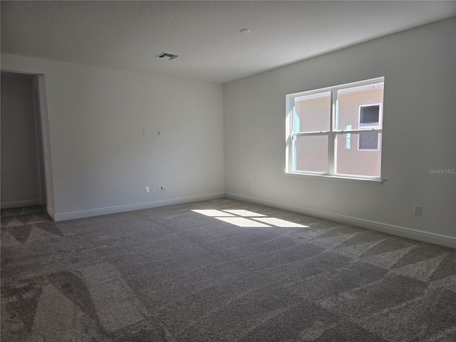 empty room with carpet flooring, visible vents, and baseboards