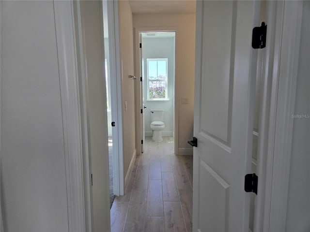 corridor with light wood-type flooring and baseboards