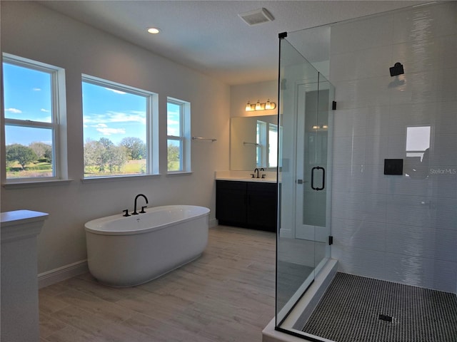 full bathroom with a soaking tub, visible vents, a shower stall, vanity, and wood finished floors