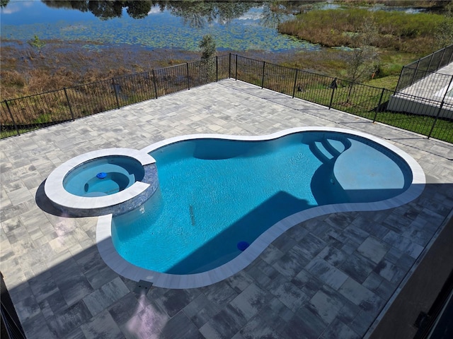 view of swimming pool featuring a pool with connected hot tub, a patio area, a water view, and fence