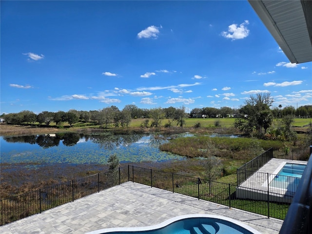 view of swimming pool featuring a patio area, a water view, and fence