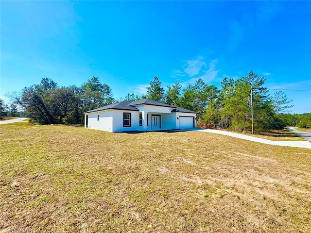 view of front of home featuring a garage, a front yard, concrete driveway, and stucco siding