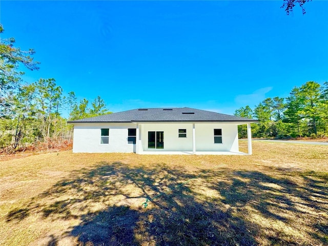 rear view of house with a yard and stucco siding