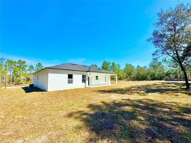 back of property with central AC, a lawn, and stucco siding