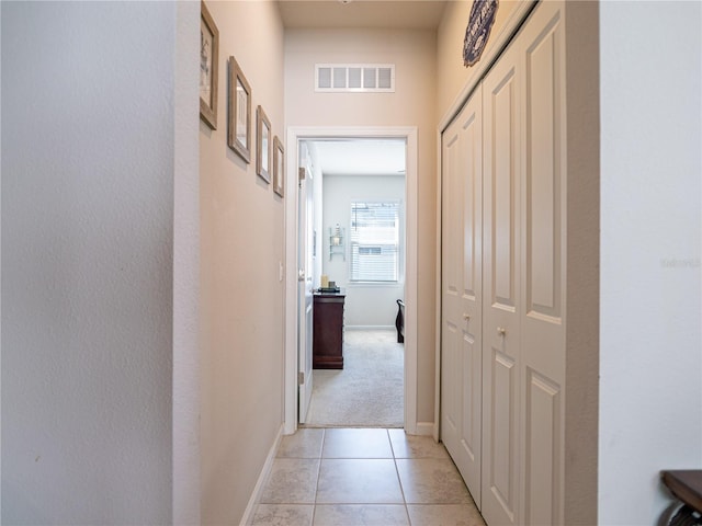 corridor featuring light tile patterned floors, baseboards, and visible vents