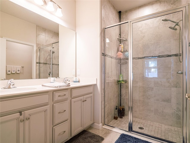 bathroom with double vanity, a stall shower, a sink, and tile patterned floors