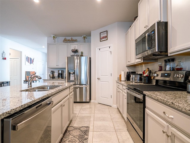 kitchen featuring light tile patterned floors, light stone counters, stainless steel appliances, a sink, and recessed lighting