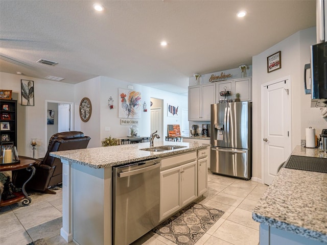 kitchen featuring visible vents, open floor plan, a kitchen island with sink, stainless steel appliances, and a sink