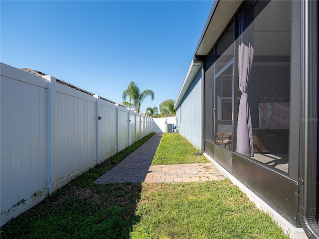 view of yard featuring central AC unit, a fenced backyard, and a sunroom