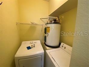 laundry area with laundry area, washing machine and dryer, and electric water heater