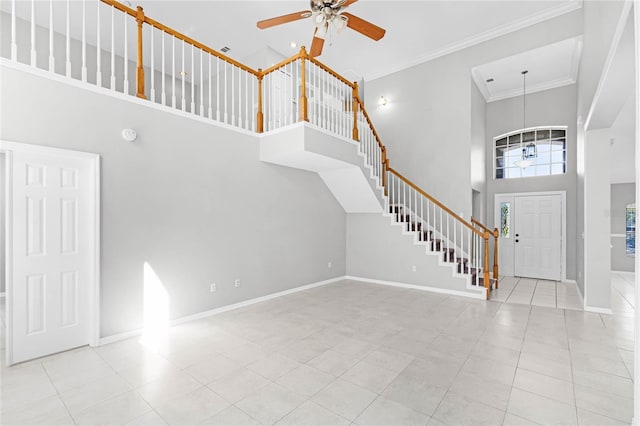 entrance foyer with baseboards, a towering ceiling, ornamental molding, tile patterned floors, and stairs