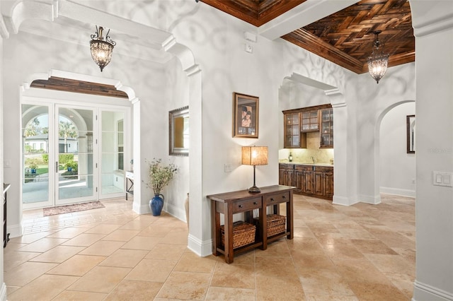 corridor with an inviting chandelier, baseboards, a high ceiling, and arched walkways