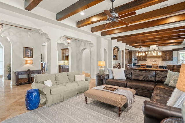 living room featuring visible vents, arched walkways, a ceiling fan, baseboards, and beamed ceiling