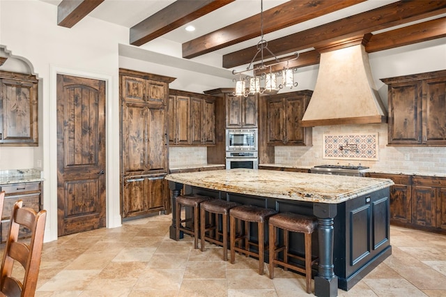 kitchen featuring tasteful backsplash, custom range hood, a breakfast bar area, a center island, and stainless steel appliances