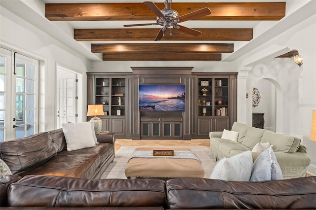 living room featuring a ceiling fan, arched walkways, french doors, and beamed ceiling