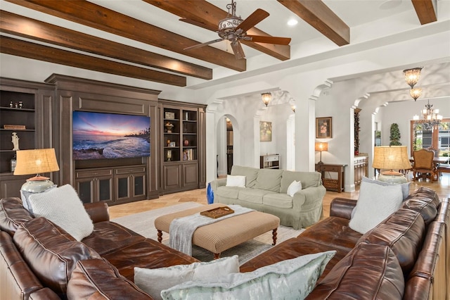 home theater room featuring arched walkways, ceiling fan with notable chandelier, and beam ceiling