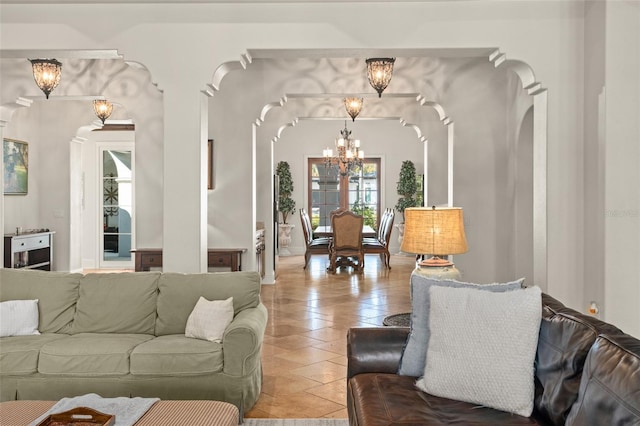 living room featuring light tile patterned floors, a chandelier, and arched walkways