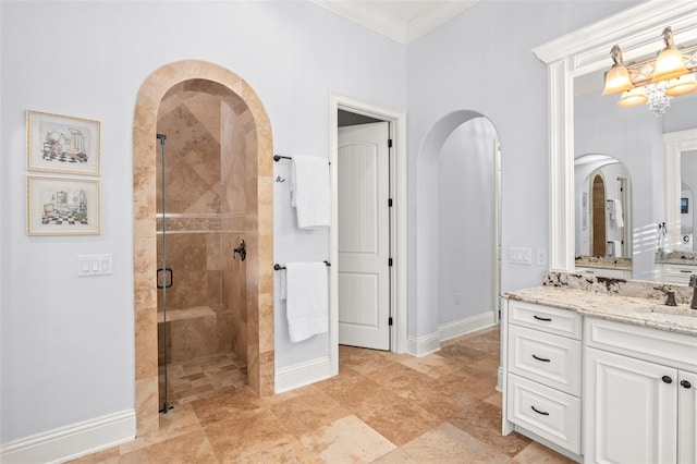 bathroom featuring an inviting chandelier, ornamental molding, a stall shower, vanity, and baseboards