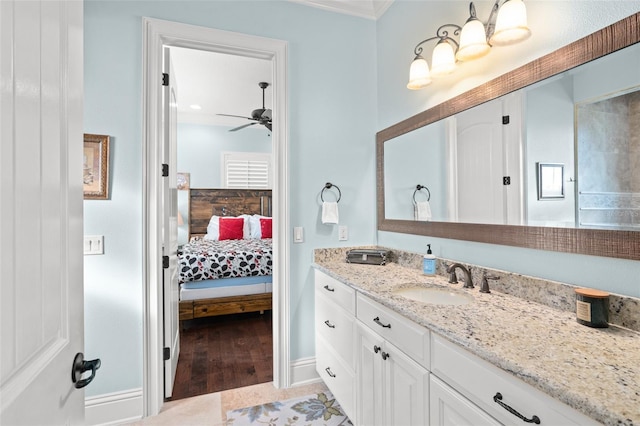 bathroom with ceiling fan, connected bathroom, wood finished floors, vanity, and baseboards