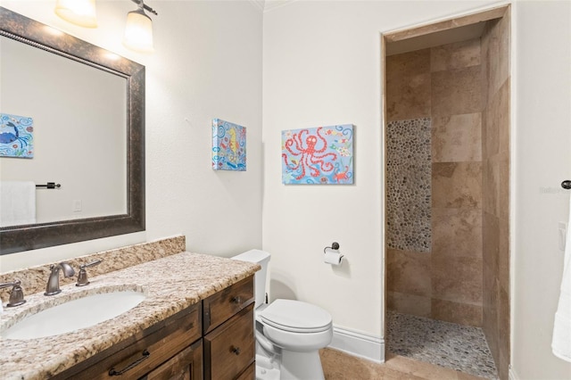 bathroom with a tile shower, vanity, and toilet