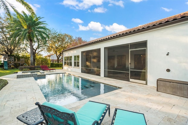 view of swimming pool featuring a patio, a pool with connected hot tub, a playground, and a sunroom