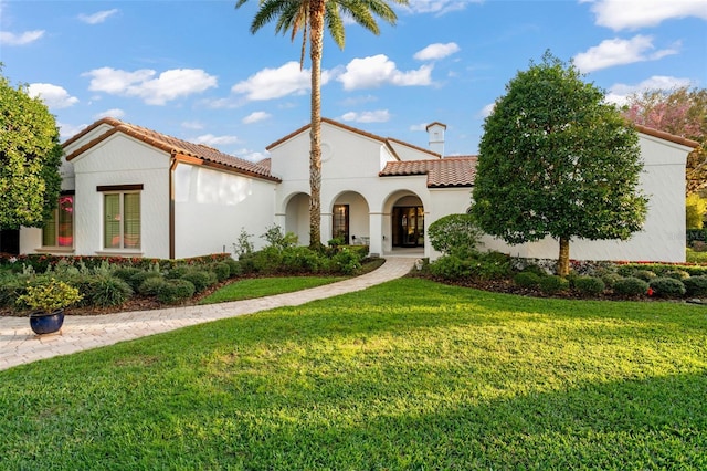 mediterranean / spanish house featuring a tiled roof, a front yard, and stucco siding