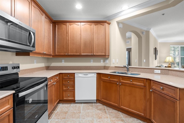 kitchen with crown molding, appliances with stainless steel finishes, light countertops, and a sink