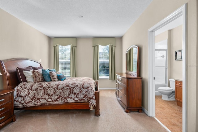 bedroom with light carpet, baseboards, a textured ceiling, and ensuite bathroom