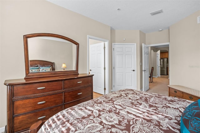 bedroom featuring visible vents, light carpet, arched walkways, and freestanding refrigerator