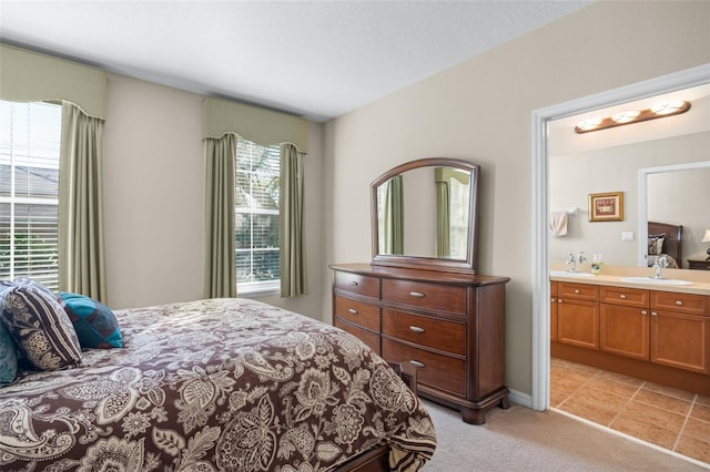 bedroom with light carpet, a sink, and ensuite bathroom