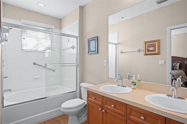 full bath with shower / bath combination with glass door, a sink, toilet, and double vanity