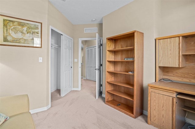 office space featuring baseboards, visible vents, and light colored carpet