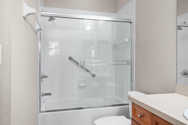 bathroom featuring enclosed tub / shower combo, a textured wall, vanity, and toilet